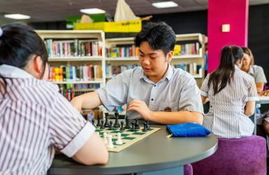 Trung playing chess in Haileybury school